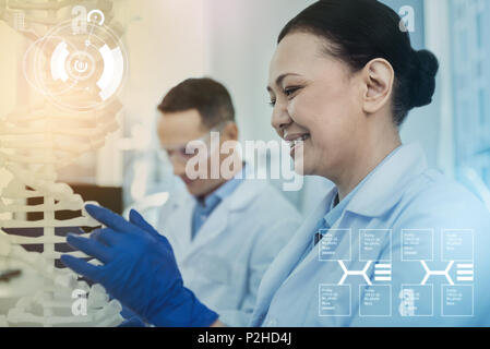 Positive Biologe Handschuhe tragen und auf die DNA-Modell Stockfoto