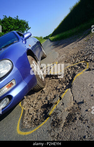 Auto fahren über riesige Schlagloch auf der Straße mit gelber Umrandung für die Instandsetzung, york Yorkshire unitedc Königreich gekennzeichnet Stockfoto