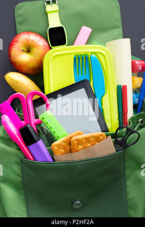 Rucksack mit Schulmaterial auf schwarzem Hintergrund. Ansicht von oben Flach Stockfoto