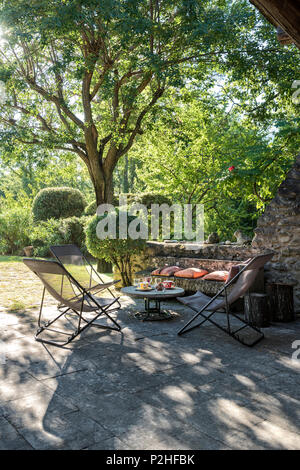 Liegestühlen und Tisch im Schatten des Baumes, Luberon. Stockfoto