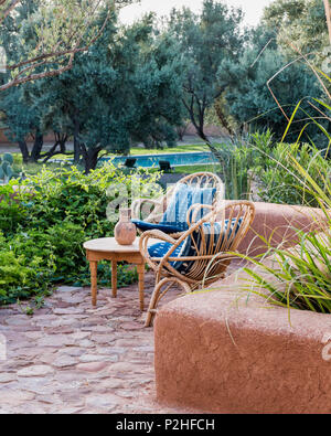 Ein paar Rattan Stühle im Garten mit Erde Mauern, Kräuter und marokkanische Wildpflanzen. Garten Design von Arnaud Casaus Stockfoto