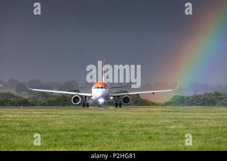 EasyJet Airbus A320 G-EZPU Rollen bei einem starken Regen Sturm vor einem Regenbogen am 18. August 2017 vom Flughafen London Luton, Bedfordshire, Großbritannien Stockfoto