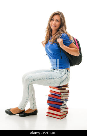 Schönen lächelnden Teenager mit Schultasche sitzend auf Stapel von Büchern und Kamera. Stockfoto