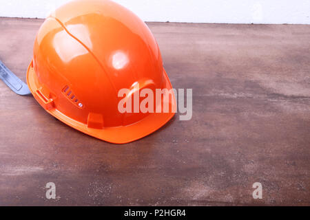 Orange Sicherheitsingenieur Helm auf braunen Hintergrund. Stockfoto