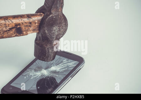 Schwarz Handy ist beschädigt, auf weißem Hintergrund, Hammer auf dem Bildschirm nach dem Schlagen, getönten Bild Stockfoto