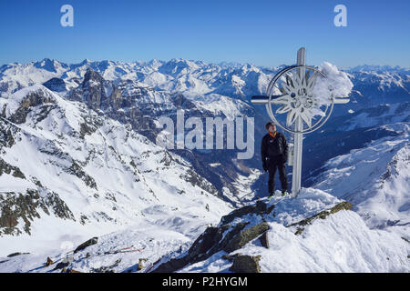 Mann zurück Langlauf am Kreuz auf dem Gipfel der Schneespitze, Stubaier Alpen mit Tribulaun und Zillertaler Alpen im Hintergrund Stockfoto