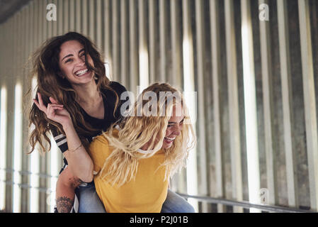Lachende junge Frau von ihrem Freund trug, während eine lustige Nacht zusammen in der Stadt Stockfoto
