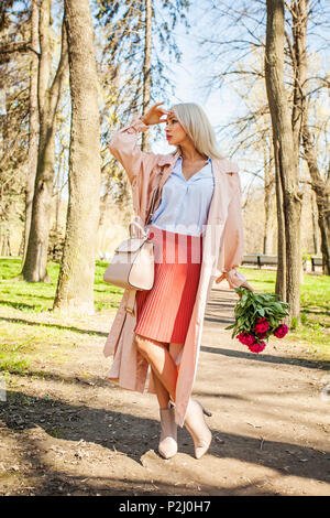Perfekte Frau mit Blumen im Freien. Blonde weibliche Modell mit Pfingstrose warten in Park Stockfoto