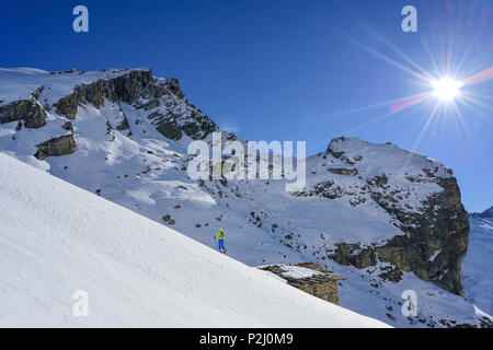 Frau back-country skiing aufsteigender Richtung Monte Salza, Überschreiten der Hütte, im Hintergrund Rocca Senghi, Monte Salza, Valle Var Stockfoto