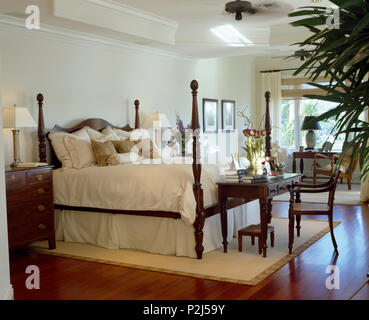 Bett mit gedrehten Spindeln und weißer Bettwäsche in großen weißen Küsten Schlafzimmer mit Holzböden Stockfoto