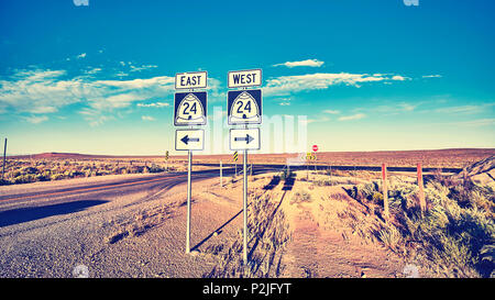 Ost oder West, retro Farben Foto von Verkehrszeichen bei Sonnenuntergang, Auswahl und Travel Concept. Stockfoto