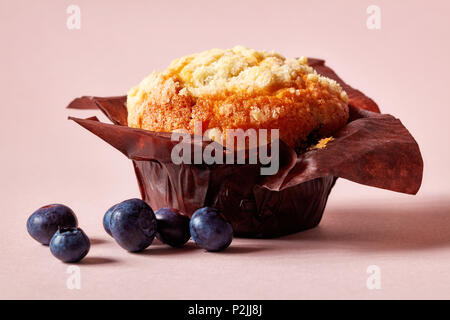 Blueberry Muffin in braunem Papier mit frischen Beeren auf rosa Hintergrund isoliert Stockfoto