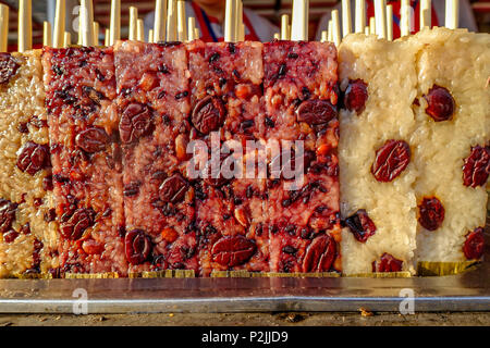 Snack Street in Peking, China. Berühmten Beijing Street Food Klebreis stick, gekochte Rechteck Lila Reis Kuchen. Stockfoto