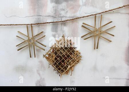 Nahaufnahme des niedlichen Wicker hölzernen Kranz aus getrockneten Zweig und Blätter an den weißen Wand Stockfoto