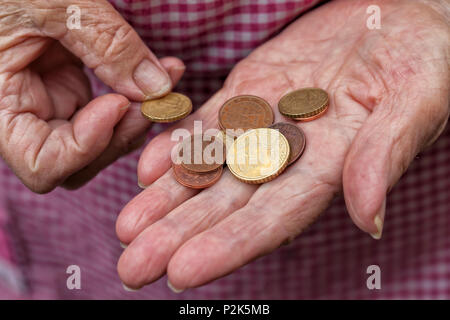 Eine ältere Dame hält ein paar Cent von Euro in den Händen. Stockfoto