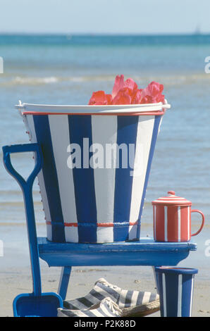 Still-Life bemalt blau + weiß gestreiften Löffel mit Spaten auf blauen Stuhl am Strand Stockfoto
