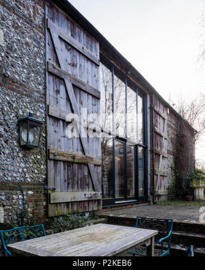 Gartenmöbel auf der Terrasse der Scheune convesrion mit großen Fenstern und Fensterläden aus Holz, Sussex Stockfoto