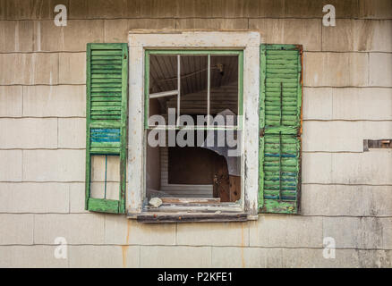 Gebrochene Fenster mit grünen Fensterläden auf alten rustikalen verlassene Scheune durch helle Herbst Laub umgeben auf einem leicht bewölkt Nachmittag am Minnewaska State Park Stockfoto
