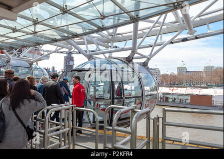 Passagiere queuing Bord eine Kapsel des London Eye, einem beliebten Riesenrad, ein Wahrzeichen von London, durch die Themse in London. Stockfoto