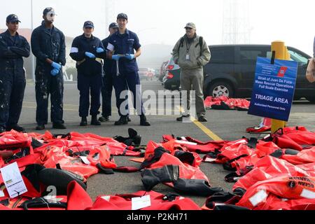 Coast Guard Mitglieder von Air Station/Sektor Field Office Port Angeles stehen auf einer triage Bereich während einer gemeinsamen Agentur Masse Rescue Übung in Port Angeles, Washington, Sept. 27, 2016. Bundes-, Landes-, Bezirks- und kanadische Behörden reagierten auf eine simulierte Schiff nehmen auf Wasser nach dem Schlagen eine In-tank-Objekt in der Nähe von ediz Haken Licht und zusammen gearbeitet, um eine einheitliche Kommandozentrale zu etablieren. (U.S. Coast Guard Foto von Petty Officer 2. Klasse Ali Flockerzi). Stockfoto