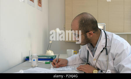 Besetzt männlichen Arzt arbeiten mit Papieren und Gespräch in seinem Büro Stockfoto