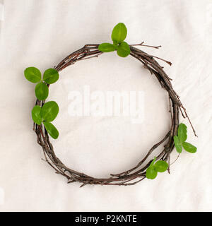 Florale Komposition. Kranz aus roools, Blätter und Blumen auf Gewebe weißen Hintergrund. Im rustikalen Stil der Wohnkultur, Flach, Ansicht von oben. St. Patrick Stockfoto
