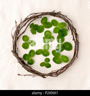 Florale Komposition. Kranz aus roools, Blätter und Blumen auf Gewebe weißen Hintergrund. Im rustikalen Stil der Wohnkultur, Flach, Ansicht von oben. St. Patrick Stockfoto
