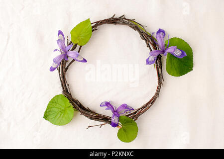 Florale Komposition. Kranz aus roools, Blätter und Blumen auf Gewebe weißen Hintergrund. Im rustikalen Stil der Wohnkultur, Flach, Ansicht von oben. Stockfoto