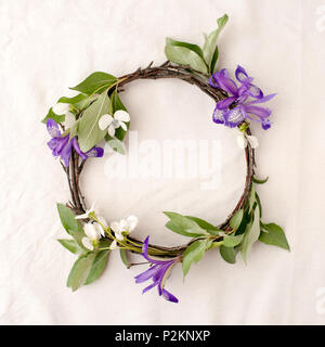 Florale Komposition. Kranz aus roools, Blätter und Blumen auf Gewebe weißen Hintergrund. Im rustikalen Stil der Wohnkultur, Flach, Ansicht von oben. Stockfoto