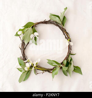 Florale Komposition. Kranz aus roools, Blätter und Blumen auf Gewebe weißen Hintergrund. Im rustikalen Stil der Wohnkultur, Flach, Ansicht von oben. Stockfoto