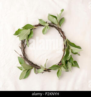 Florale Komposition. Kranz aus roools, Blätter und Blumen auf Gewebe weißen Hintergrund. Im rustikalen Stil der Wohnkultur, Flach, Ansicht von oben. Stockfoto
