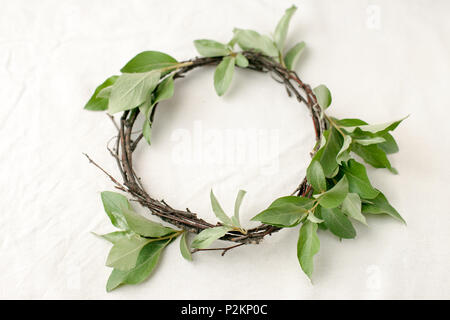 Florale Komposition. Kranz aus roools, Blätter und Blumen auf Gewebe weißen Hintergrund. Im rustikalen Stil der Wohnkultur, Flach, Ansicht von oben. Stockfoto