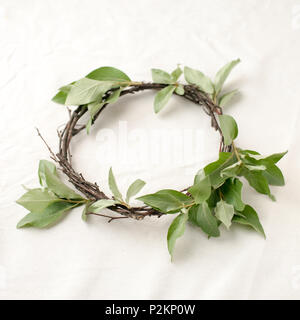 Florale Komposition. Kranz aus roools, Blätter und Blumen auf Gewebe weißen Hintergrund. Im rustikalen Stil der Wohnkultur, Flach, Ansicht von oben. Stockfoto