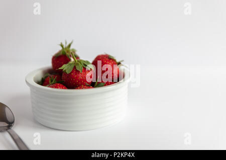 Erdbeeren und Sahne in einem weißen Teller auf weißem Hintergrund Stockfoto