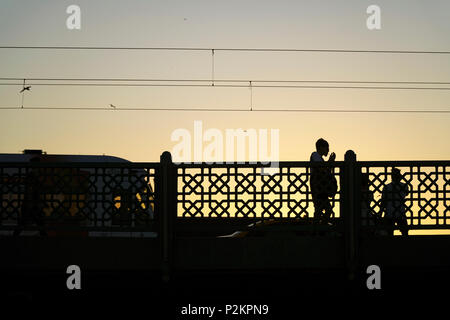 Istanbul, Türkei - 12. Juni 2018: Silhouetten auf der Galata Brücke in Istanbul. Zwei Männer stehen, wenn die Straßenbahn vorbei ist auf der Brücke. Stockfoto