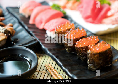 Sushi mit Stäbchen und Sojasauce. Sushi Roll japanisches Essen im Restaurant. Lachs Rogen Sushi mit Lachs, Gemüse, fliegender Fischrogen und Kaviar Stockfoto