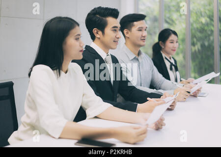 Fröhliche business Mann sitzt mit anderen Profis warten auf Job Interview. Gruppe von Menschen warten auf Job Interview im Büro Stockfoto