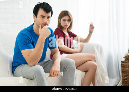 Frustriert Mann Mann sitzt neben seiner Frau, wenn sie in der Schwangerschaft Test in der Frau die Hand. Keine gute Nachrichten am Morgen Stockfoto