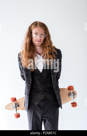 Stilvolle Geschäftsmann mit lockigem Haar holding Longboard oben wieder auf Weiß isoliert Stockfoto