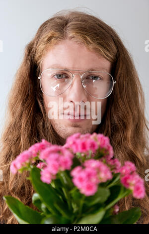 Portrait von stilvollen Mann mit lockigem Haar mit Blumenstrauß aus rosa Blüten an Kamera suchen Stockfoto