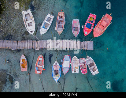 Ein Blick von Oben auf die bunten Fischerboote Verankerung in der Marina neben Jetty hölzerne Seebrücke, Griechenland Stockfoto