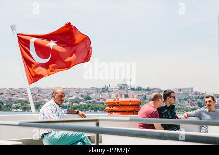 Istanbul, 17. Juni 2017: Lokale Bewohner bewegen auf dem Wasser mit der Fähre oder im Boot. Ein Mann sitzt neben der türkischen Flagge. In der Nähe eine Gruppe von Freunden comm Stockfoto