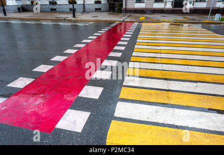 Fußgängerüberweg mit weißen, gelben und roten Linien auf dem Asphalt Stockfoto