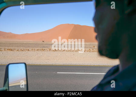 Blick durch weg Fenster der hellen roten dramatische Dünen entlang der Straße in Sossusvlei, Namibia Stockfoto