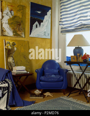 Großen Gemälden an der Wand über hellen Blau Leder Sessel in der Ecke von Wohnzimmer mit gestreiften Vorhang am Fenster Stockfoto