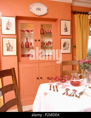 Verglaste Türen auf Alkoven Schrank mit Sammlung von cranberry Glas in terrakottafarbenen Esszimmer Stockfoto