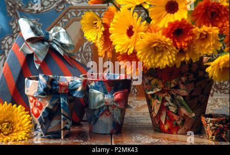 In der Nähe von orange Tagetes in Stoff Blumentopf auf dem Tisch neben dem blauen Stoff Blumentöpfe Stockfoto