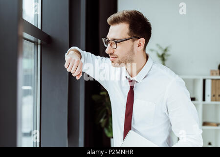 Schöne stilvolle Geschäftsmann mit Laptop auf Fenster in modernen Büro Stockfoto