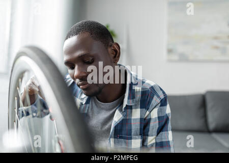 Ernsthafte stattlichen afro Mann Fahrrad zu Hause reparieren Stockfoto