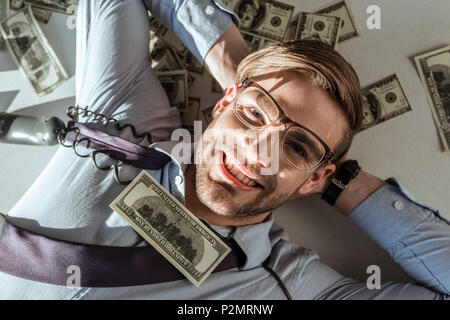 Junge reiche Geschäftsmann liegen auf dollarscheine Stockfoto
